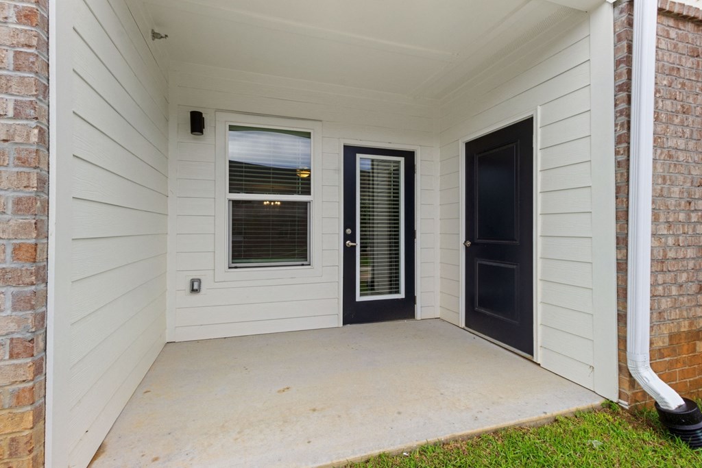 the front porch of a white house with a black door
