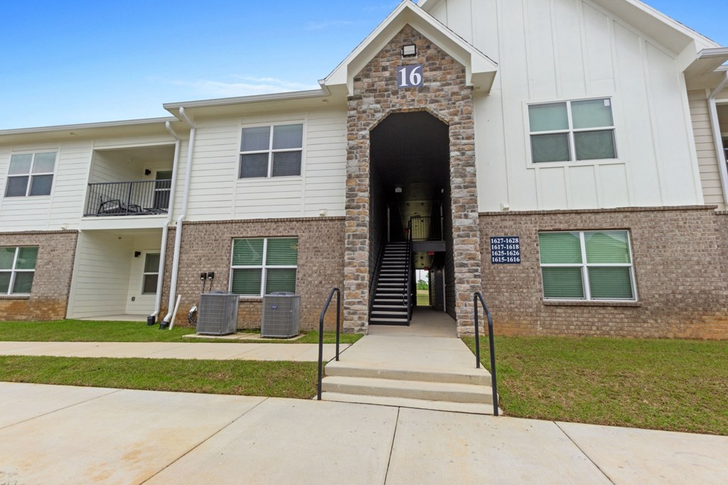 an exterior view of an apartment building with stairs and a sidewalk