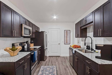 A kitchen with dark wood cabinets and granite countertops.