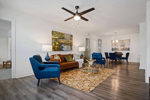 A living room with a blue chair and a painting on the wall.