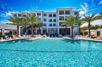 a large swimming pool with palm trees in front of a building at Altis Twin Lakes Apartments, Kissimmee, Florida