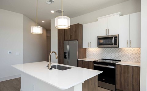 A modern kitchen with a white countertop and stainless steel appliances.