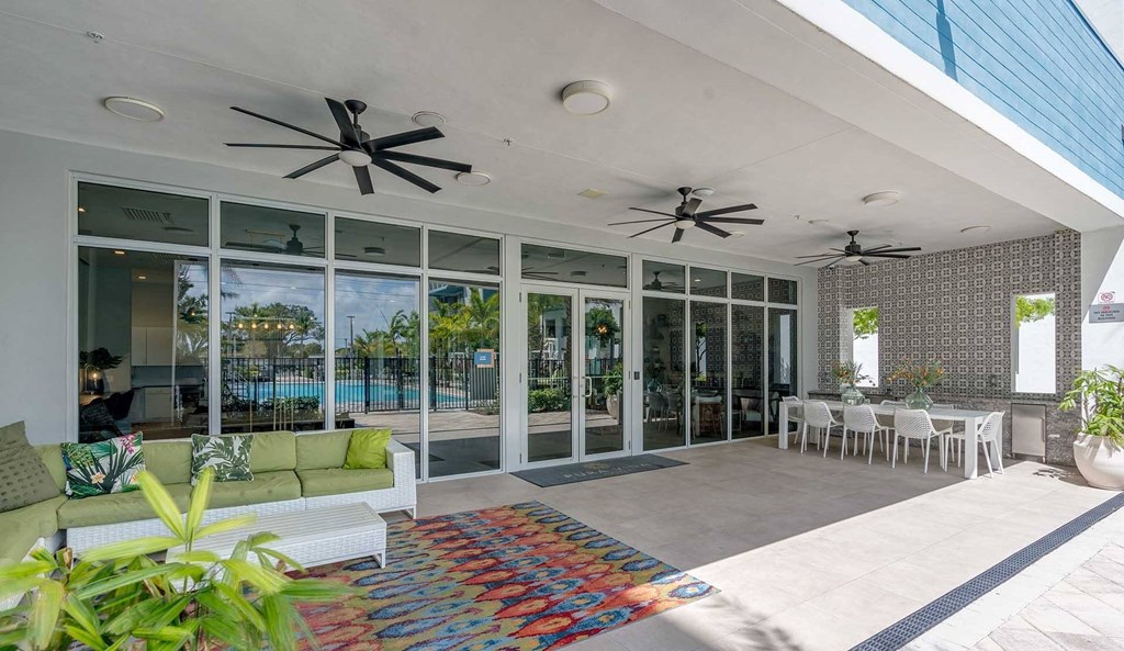 A patio with a white couch and a colorful rug.
