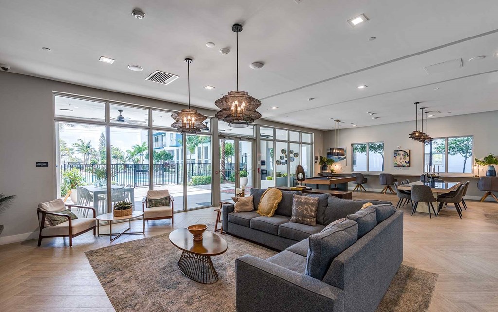 A spacious living room with a grey sofa and a large window.