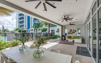 A patio with a table, chairs, and a ceiling fan.