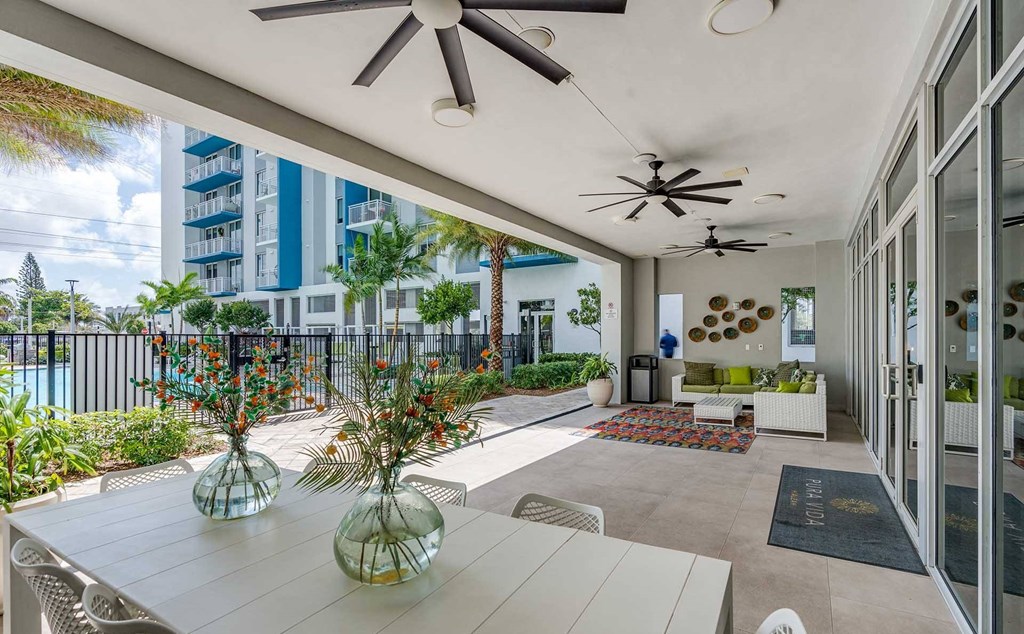 A patio with a table, chairs, and a ceiling fan.