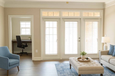 A blue chair sits in a room with a desk and a couch.