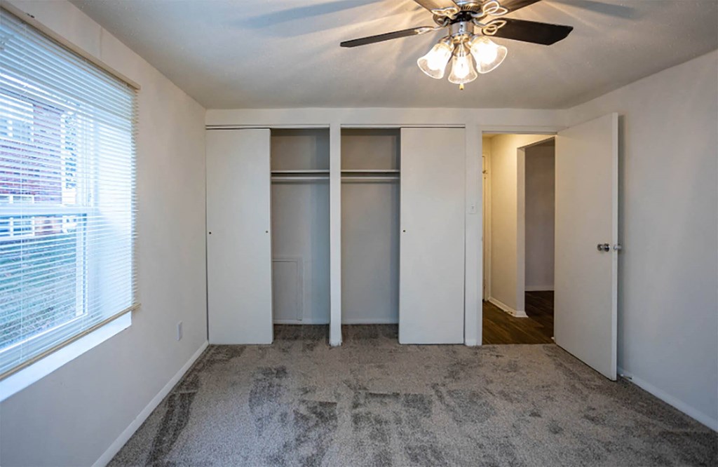 a bedroom with white walls and a ceiling fan