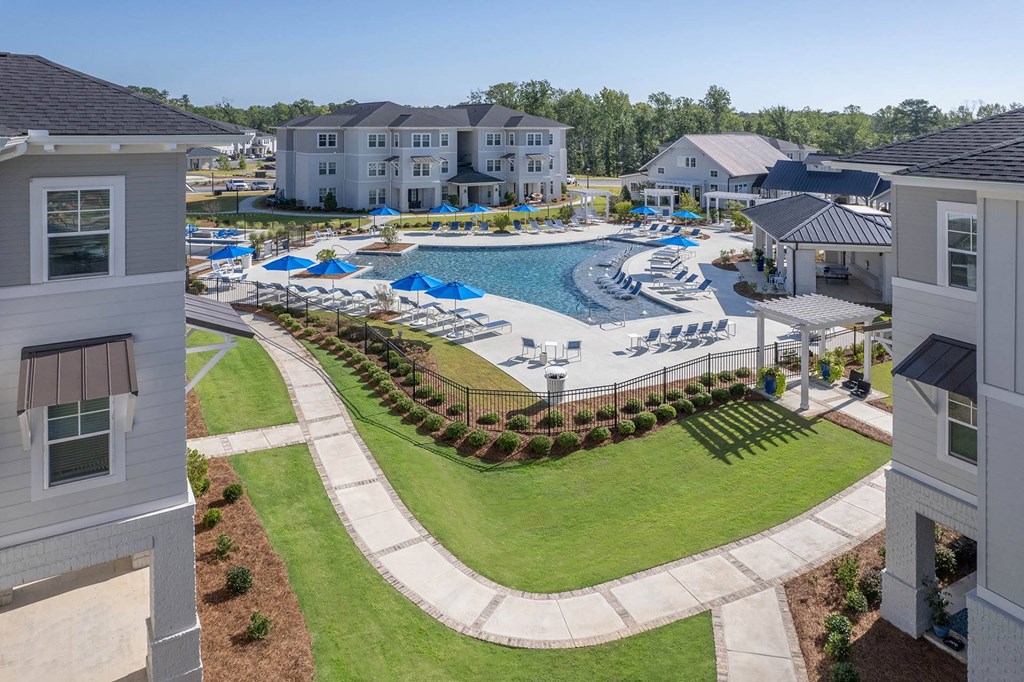 an aerial view of a resort style pool with lounge chairs and umbrellas
