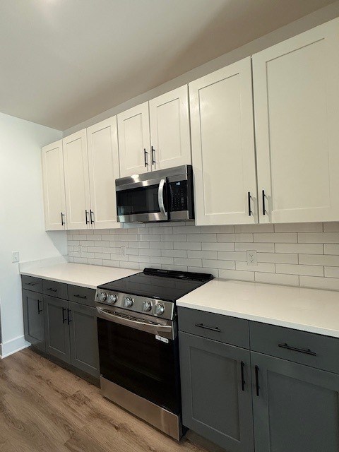 A kitchen with a black stove top oven and white countertops.