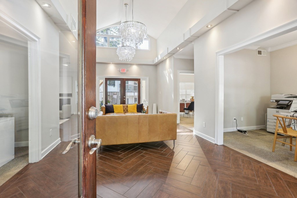 A hallway with a wooden floor and a chandelier hanging from the ceiling.