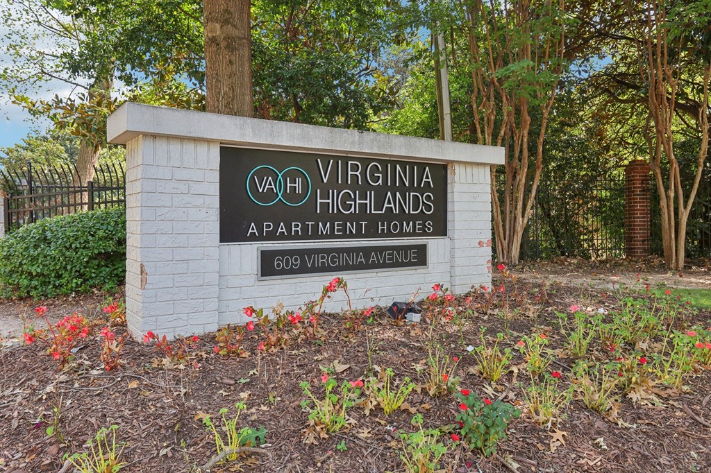 A sign for Virginia Highlands Apartment Homes stands in front of a tree.