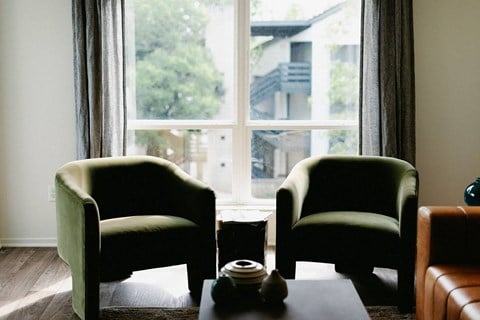 two green chairs in front of a window in a living room