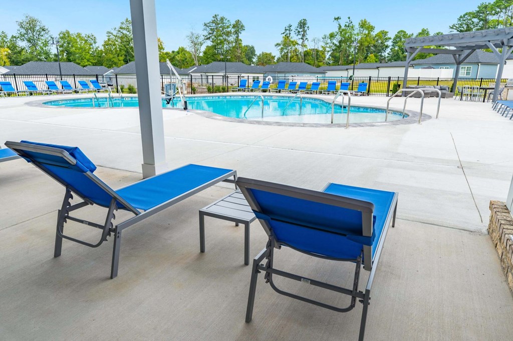 two blue lounge chairs and a table in front of a pool