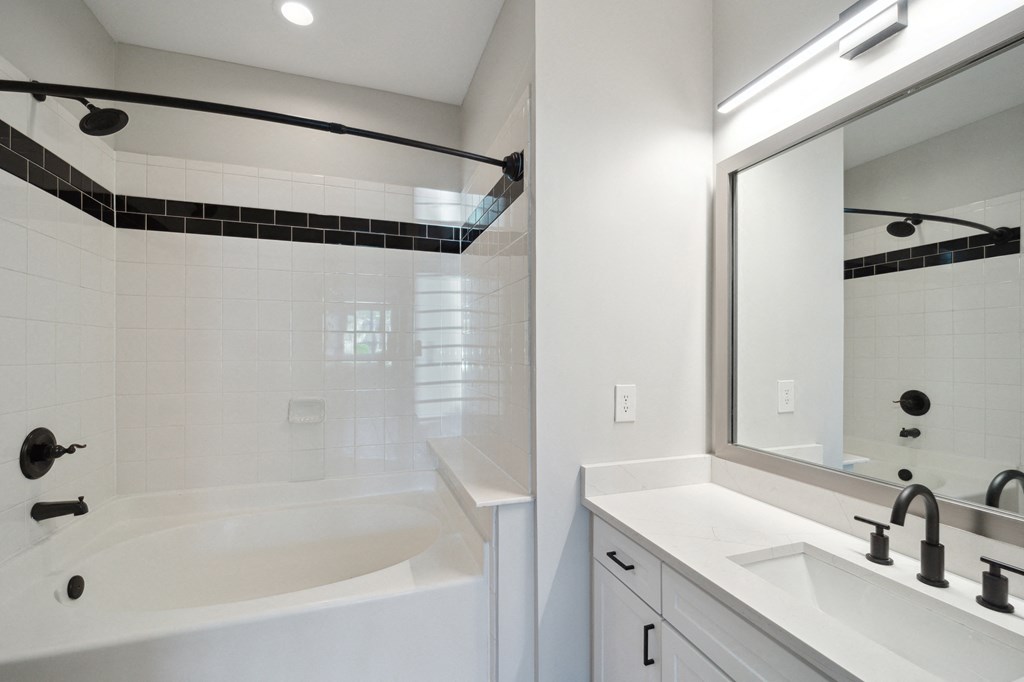 a bathroom with a tub and a sink and a mirror