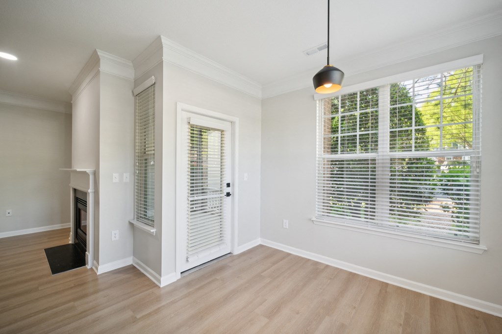 an empty living room with a large window and a door to a hallway
