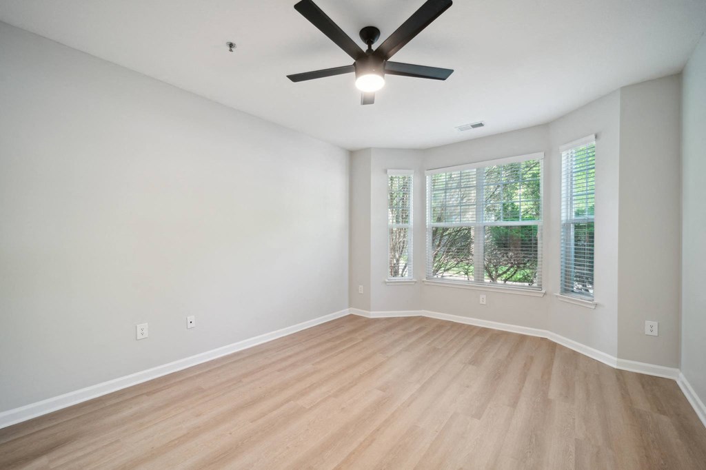 an empty living room with a ceiling fan and a window
