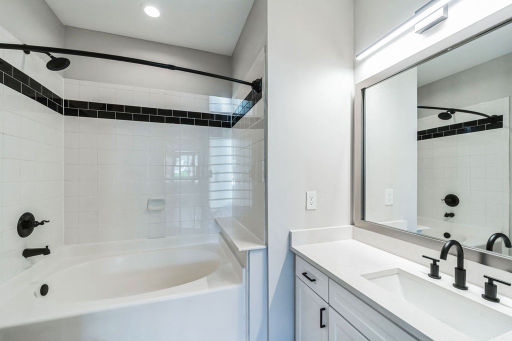 a bathroom with a tub and a sink and a mirror