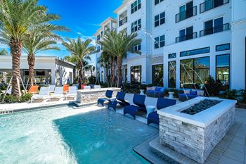 a pool with lounge chairs and a fountain in front of a building at Altis Twin Lakes Apartments, Kissimmee