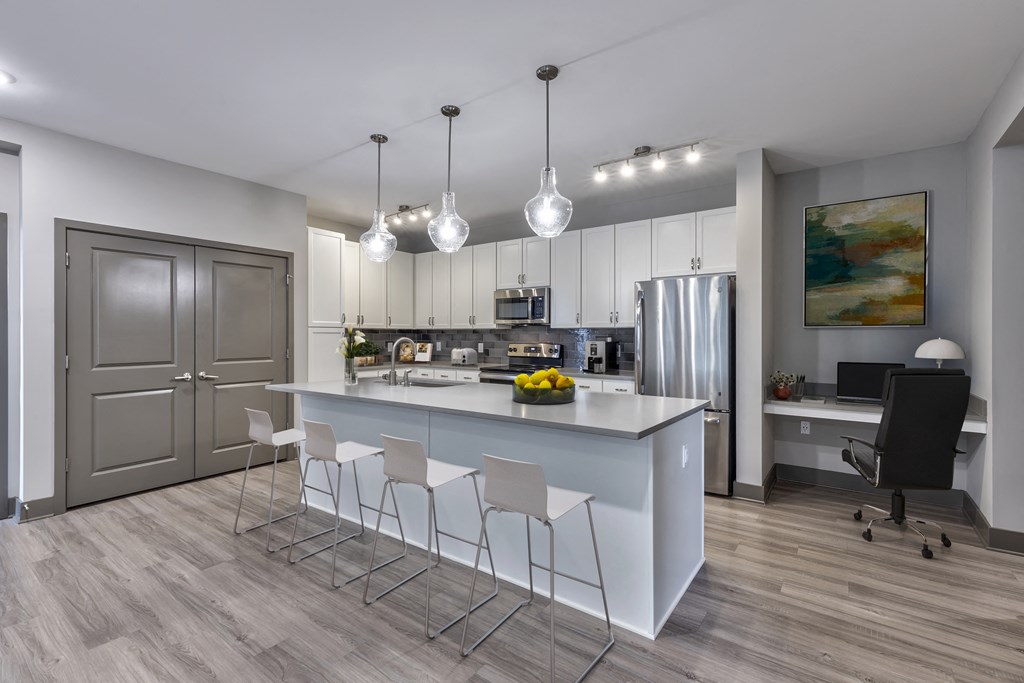 a kitchen with white cabinets and a large island with chairs