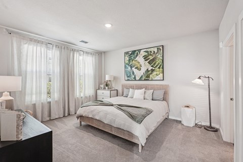 A bedroom with a large bed and a painting on the wall.