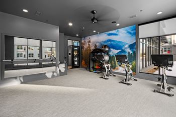 A modern gym with a large mirror and exercise bikes.
