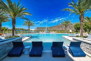 A pool area with lounge chairs and palm trees