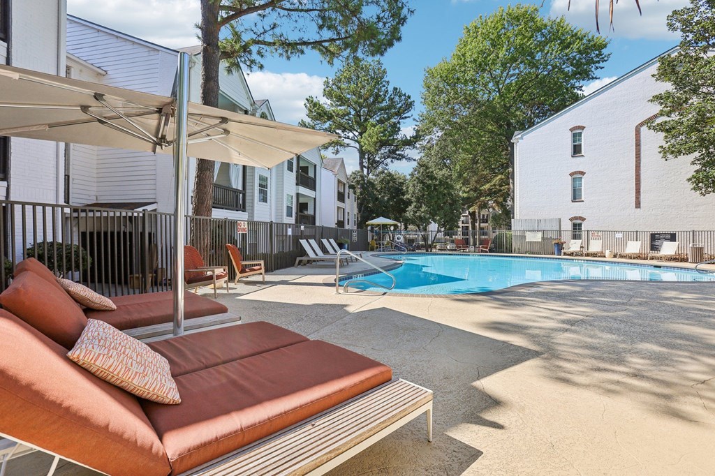 A pool area with a sun lounger and a white umbrella.