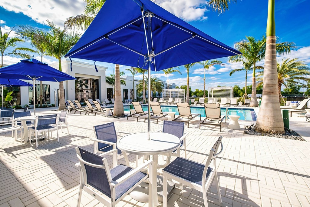 a patio with tables and chairs and umbrellas next to a pool
