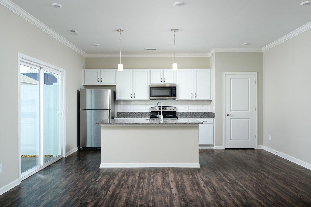 a white kitchen with a island and a stainless steel refrigerator