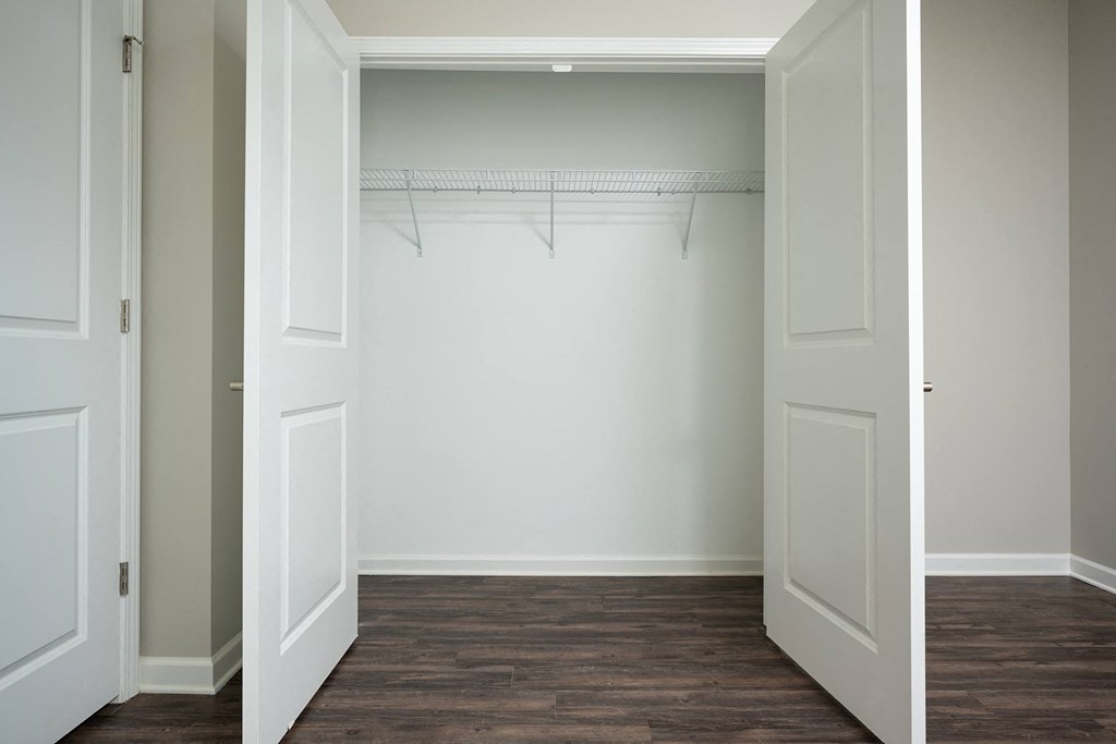 a closet with white doors and a wood floor