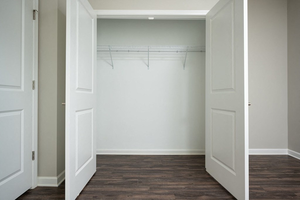 an empty closet with white doors and a wood floor