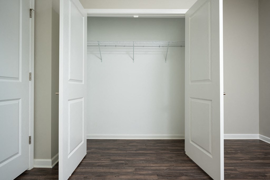 an empty closet with white doors and a wood floor