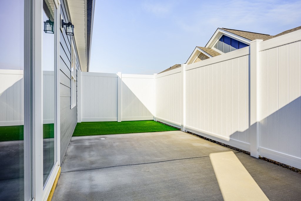 a white fence in front of a house with a driveway
