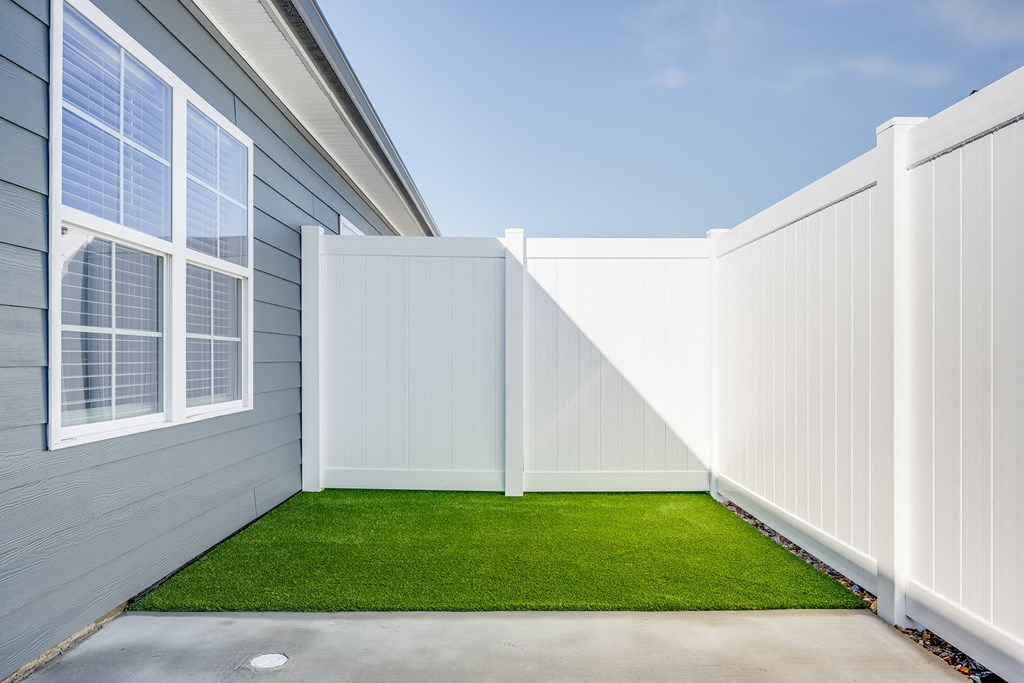 a white fence with a green lawn in front of a house