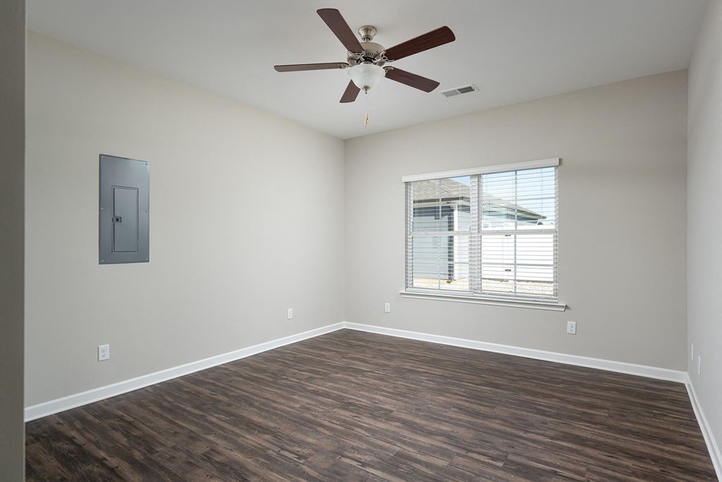 an empty living room with a ceiling fan and a window