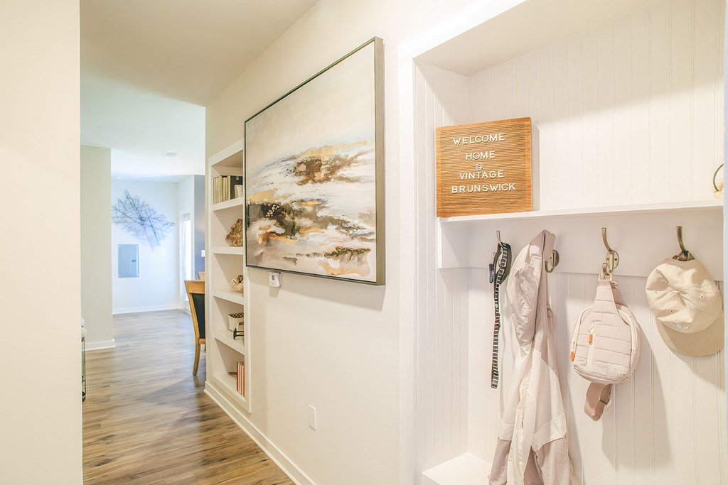 a hallway in a home with white walls and a white closet and a wall hanging