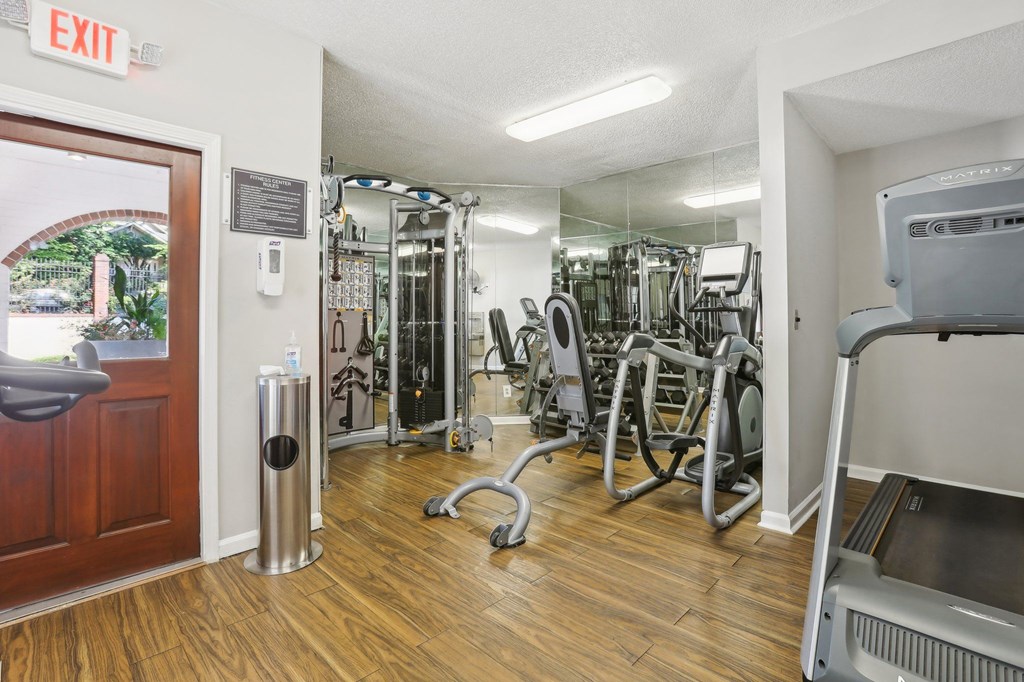 A gym with a variety of equipment including a treadmill, weights, and a mirror.