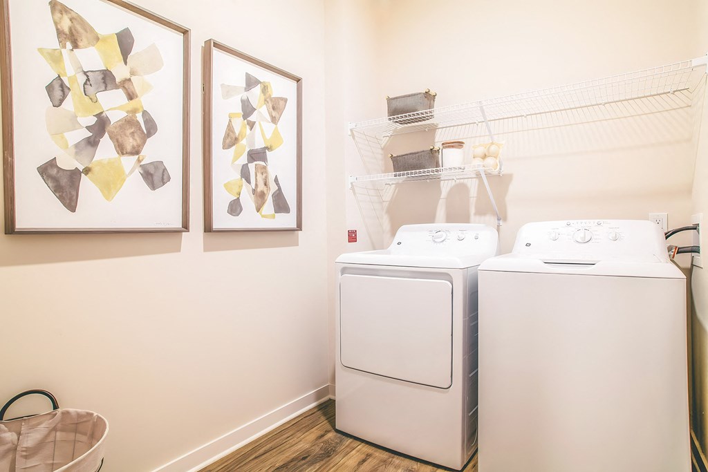 a washer and dryer in a laundry room with two paintings on the wall