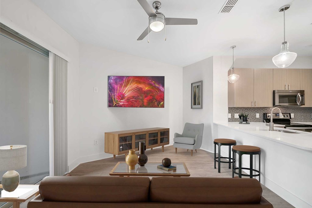 A modern living room with a brown sofa and a painting on the wall.