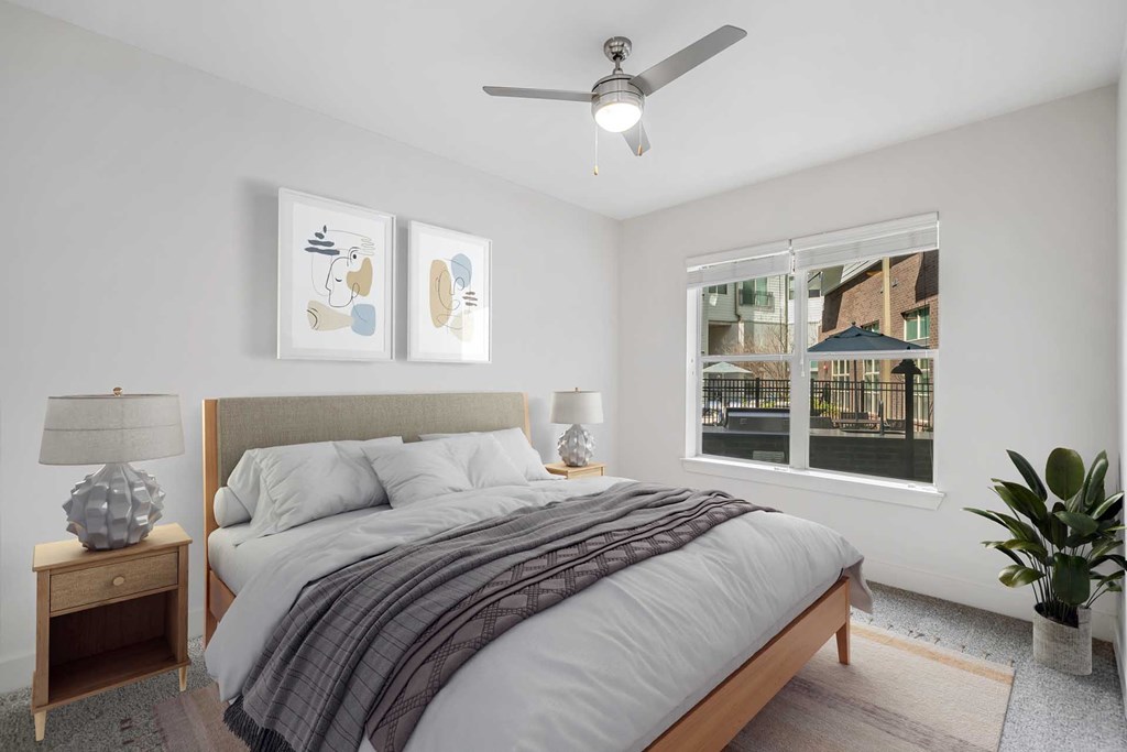 A bedroom with a bed, a ceiling fan, and two framed pictures on the wall.