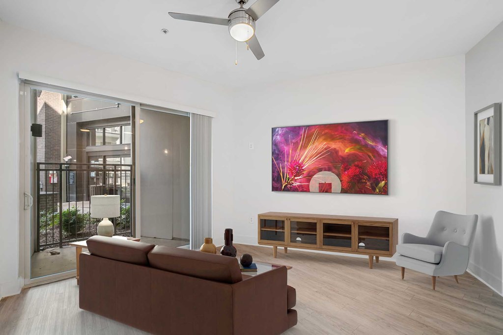 A living room with a brown couch, a grey armchair, a wooden cabinet, and a painting on the wall.