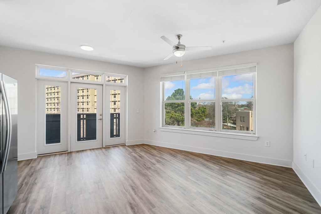 A room with a ceiling fan and a large window with a view of the outside.
