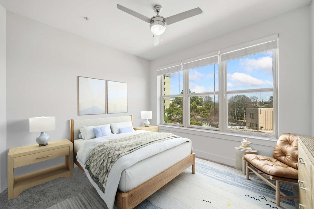 A bedroom with a large bed, a chair, and a ceiling fan.