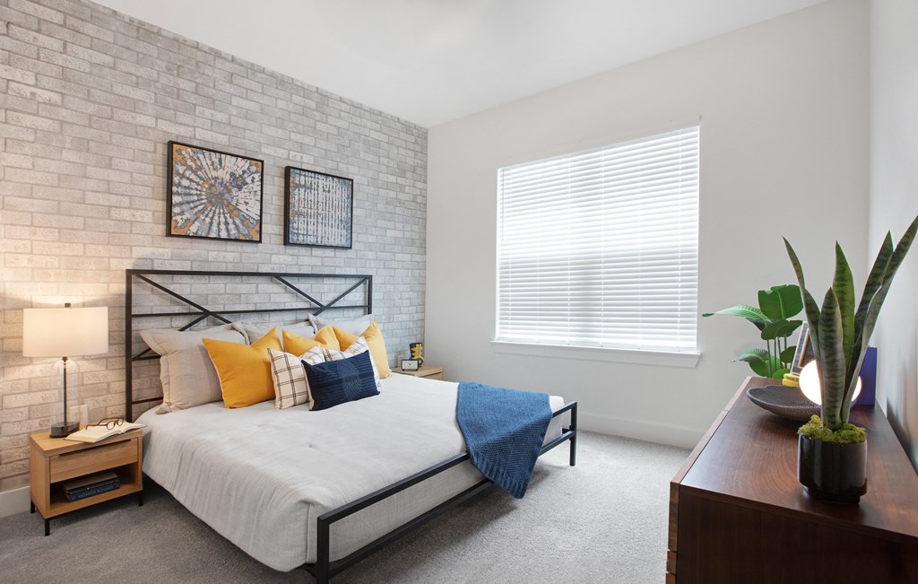 3 BR Apartments in Norcross GA - The Darnell - Furnished Bedroom with Carpeted Floors, Bed, Window, Nightstands, Lamps, and Dresser