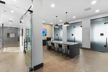 A modern office space with a glass wall and a long table with chairs.