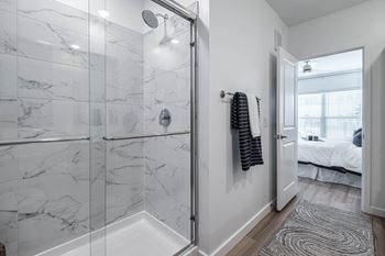 A bathroom with a marble tile shower and a towel hanging on the wall