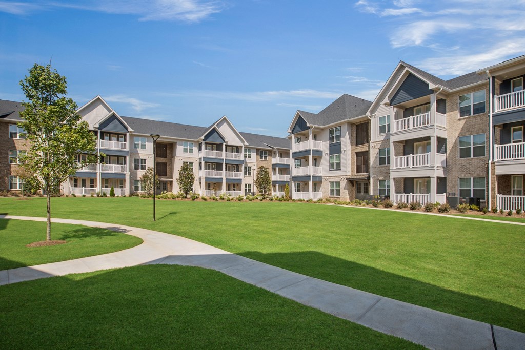 an exterior view of an apartment complex with a large green lawn
