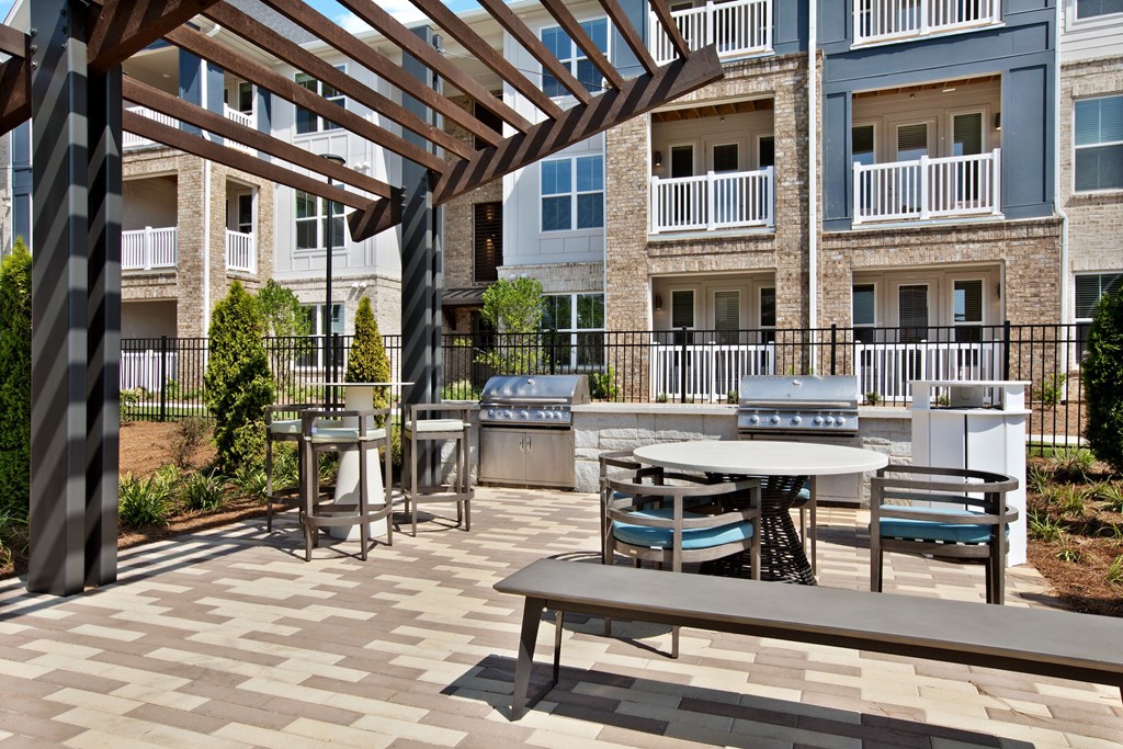 an outdoor patio with tables and benches at the bradley braddock road station apartments