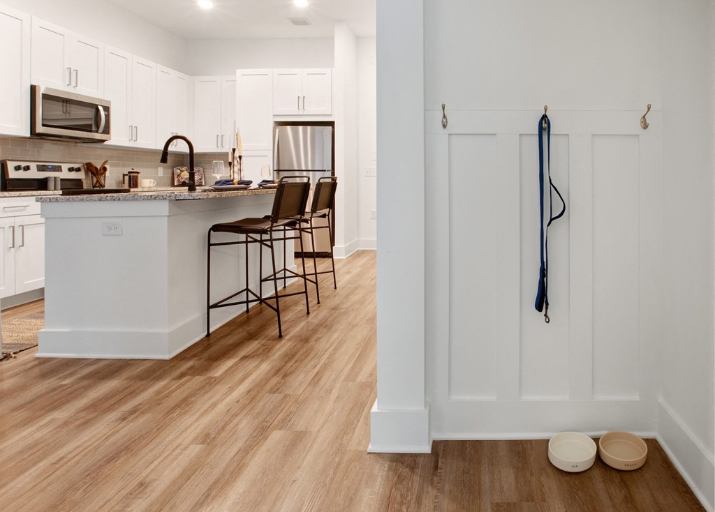 a kitchen with white cabinets and a large island with a breakfast bar and stools